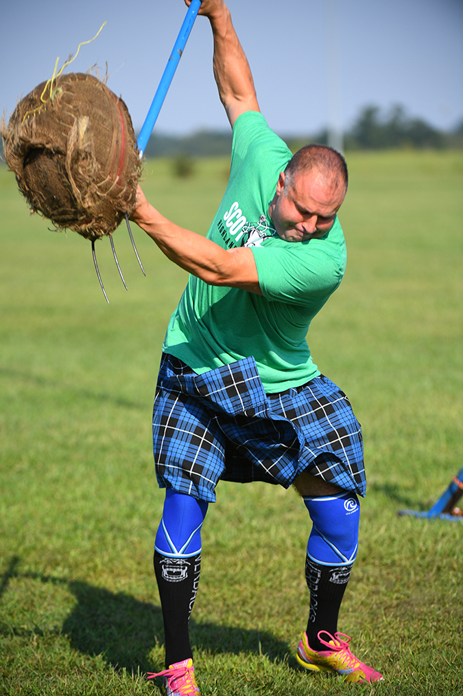 Tedd tosses a sheaf – a 16-pound burlap-covered bale of straw – with a pitchfork as high as possible. Tedd tosses a sheaf – a 16-pound burlap-covered bale of straw – with a pitchfork as high as possible.