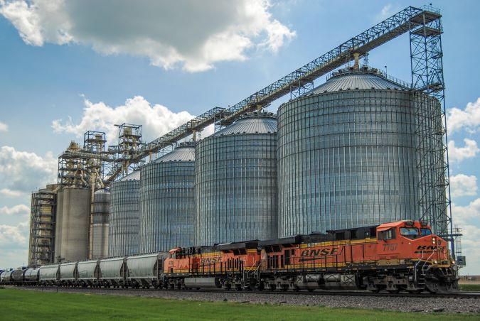A BNSF grain train passes a grain facility A BNSF grain train passes a grain facility