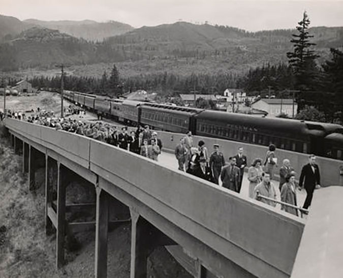 A crowd of people walking up a ramp next to an SP&S train at North Bonneville Station on June 29, 1945 A crowd of people walking up a ramp next to an SP&S train at North Bonneville Station on June 29, 1945